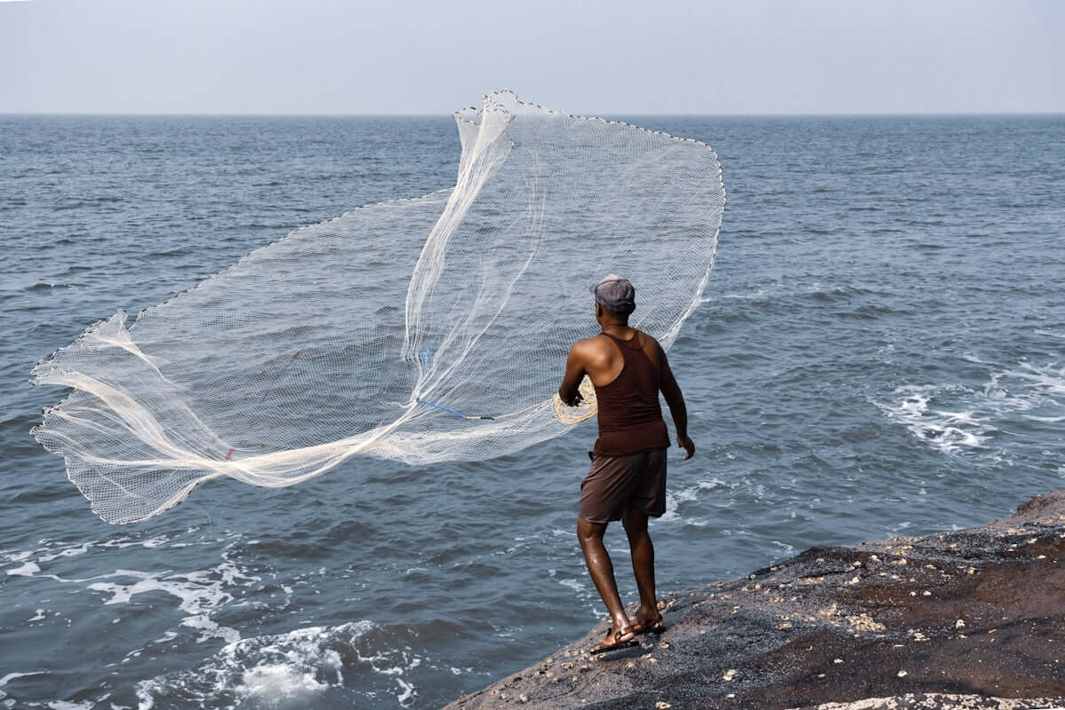 Maximize Your Catch A Guide to Using 1G-5 Fishing Net Floats with a fisherman casting a net into the ocean.