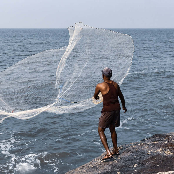 Maximize Your Catch A Guide to Using 1G-5 Fishing Net Floats with a fisherman casting a net into the ocean.