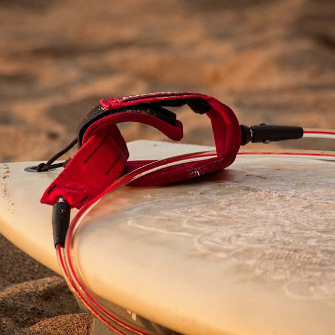 Exploring the Pro Hunter Surf Tackle Kit 65Pc with red surfboard leash on sandy beach.