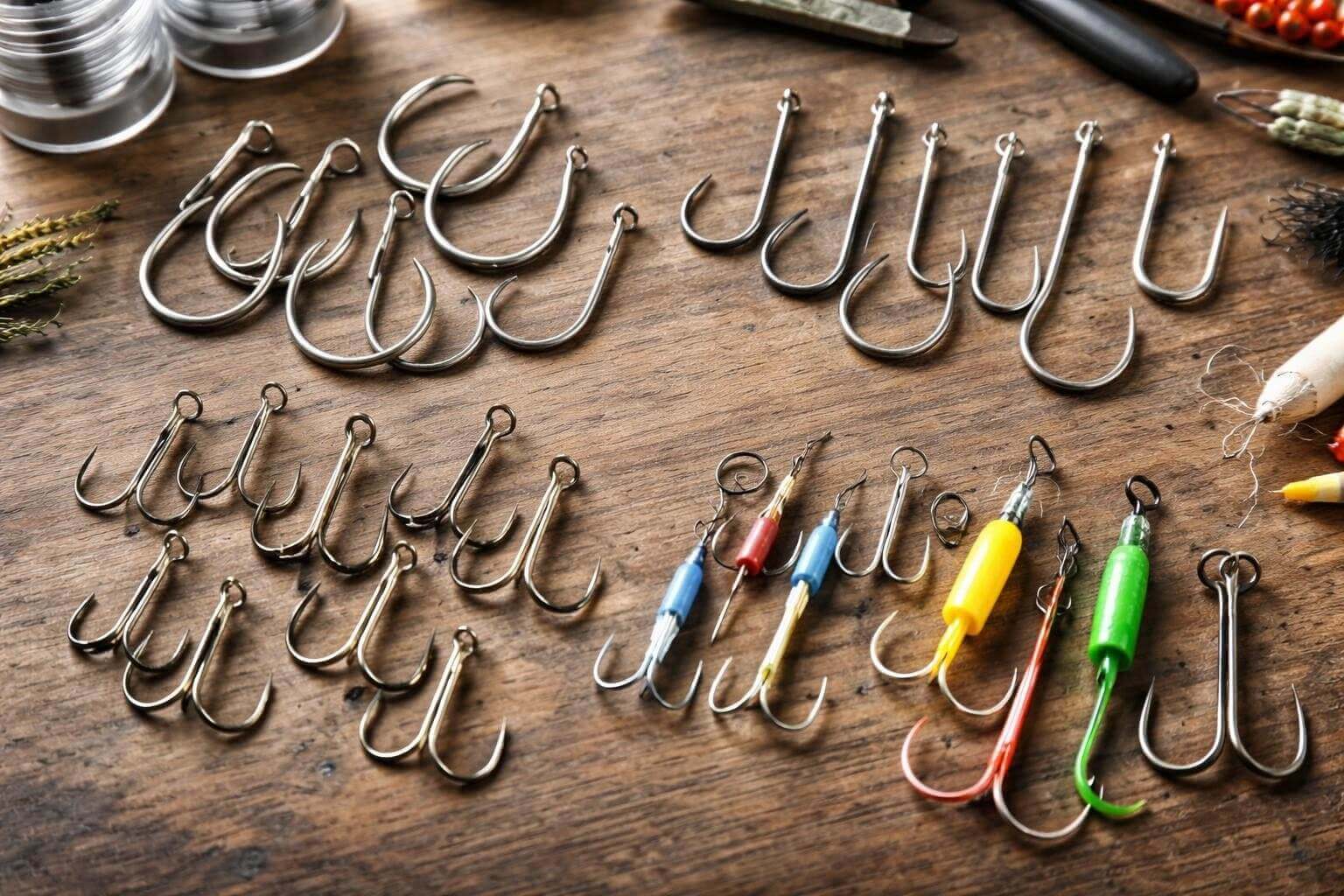 Fishing Hooks NZ Complete Guide for Commercial & Sport - a variety of fishing hooks laid out on a wooden surface.