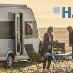 Couple enjoying outdoor cooking with Hartal Doors on their camper by the beach during sunset. Product Spotlight Hartal Doors.