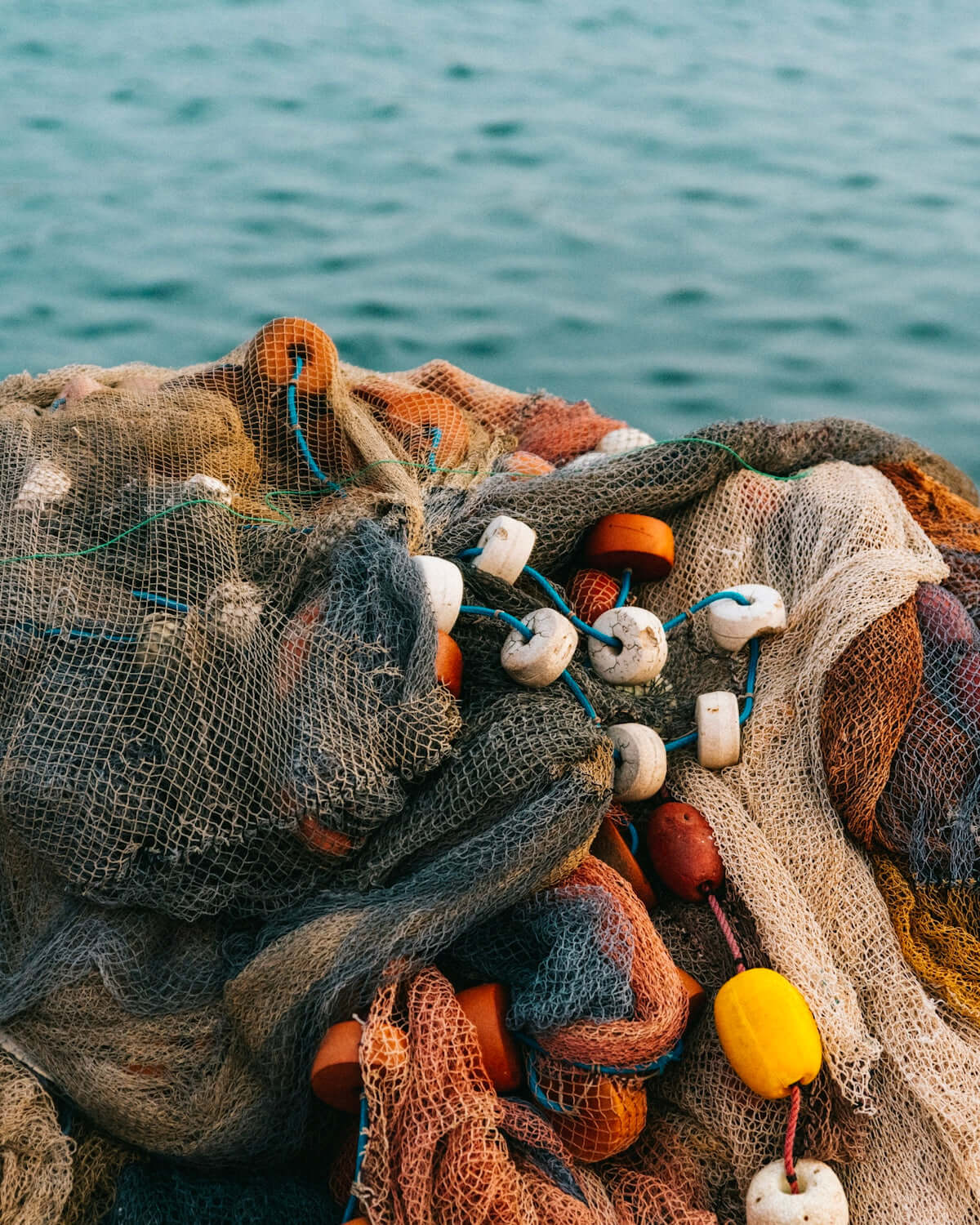 Benefits of Using 1G5 8mm Hole Fishing Net Floats with colorful buoys and mesh netting near the water.