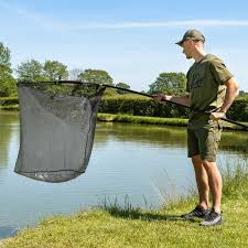 Person using a landing net beside a pond, showcasing Landing Nets & Fishing Tools in New Zealand.