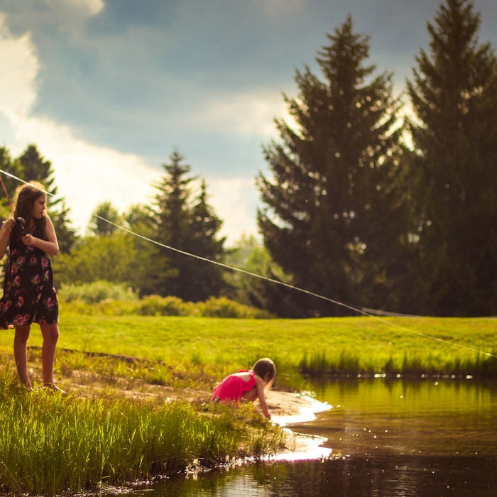 girl standing green grass field beside lake during daytime