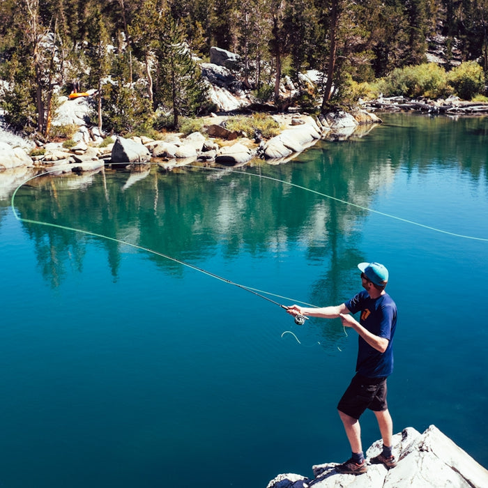a man standing on top of a rock next to a lake