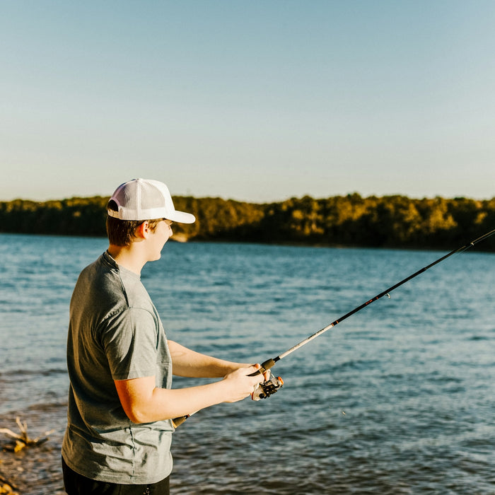 man in grey t-shirt fishing on lake during daytime