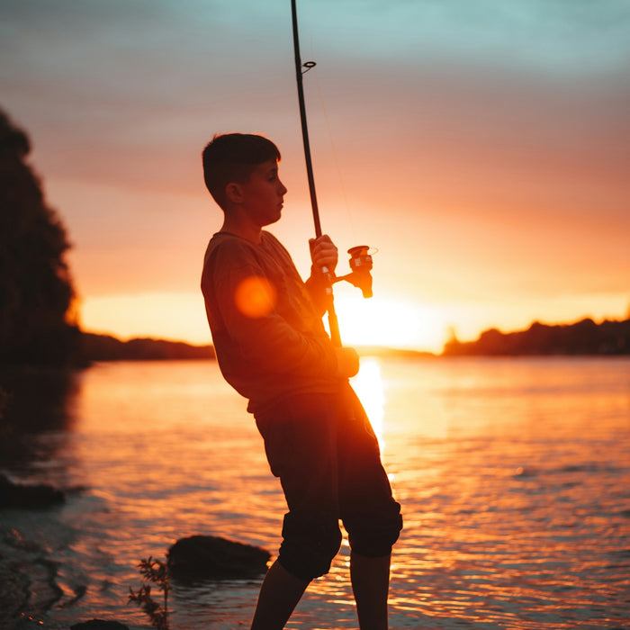 silhouette of man holding fishing rod during sunset