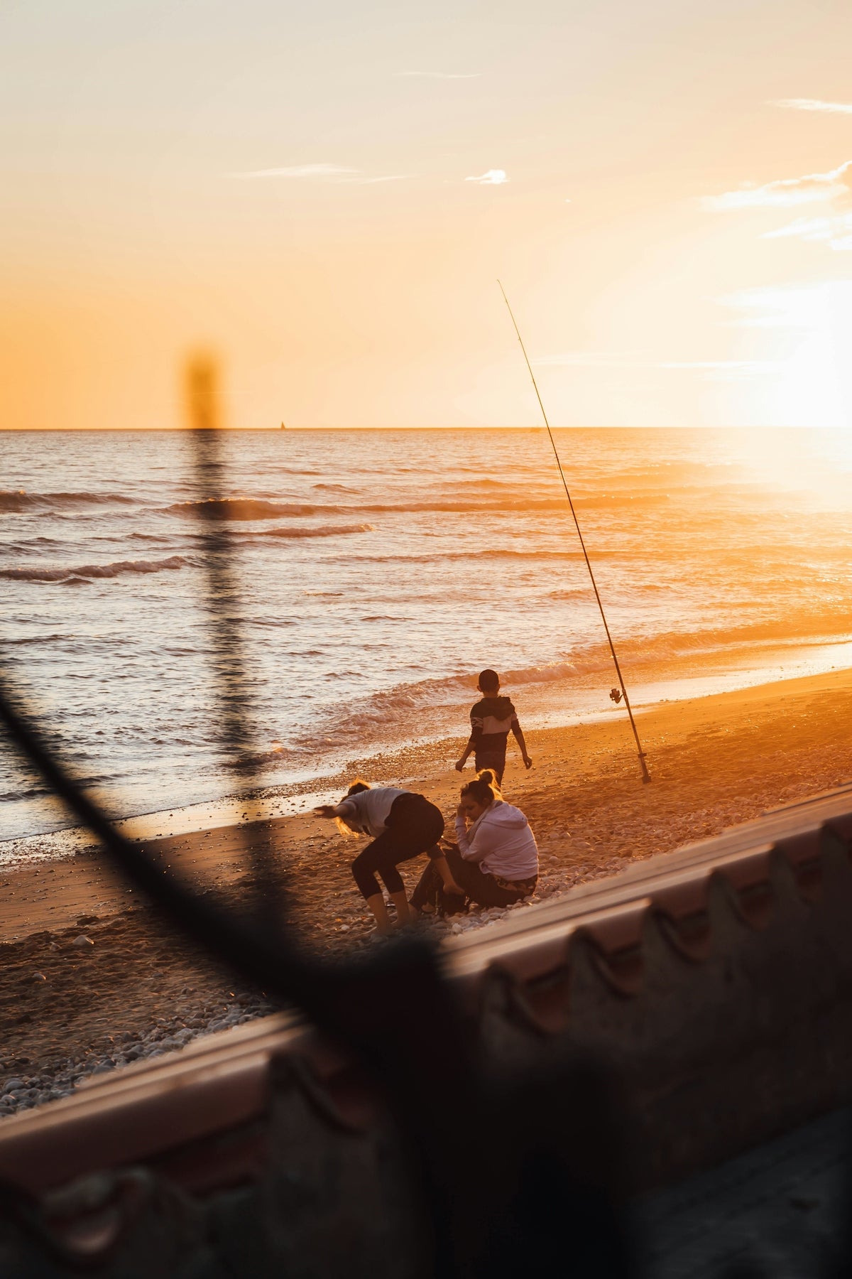 a couple of people on a beach with a fishing pole