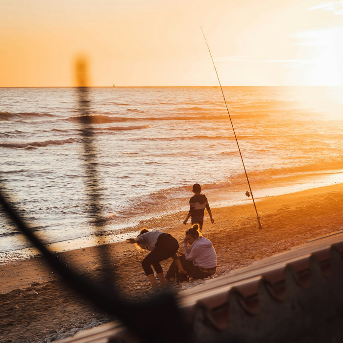 a couple of people on a beach with a fishing pole
