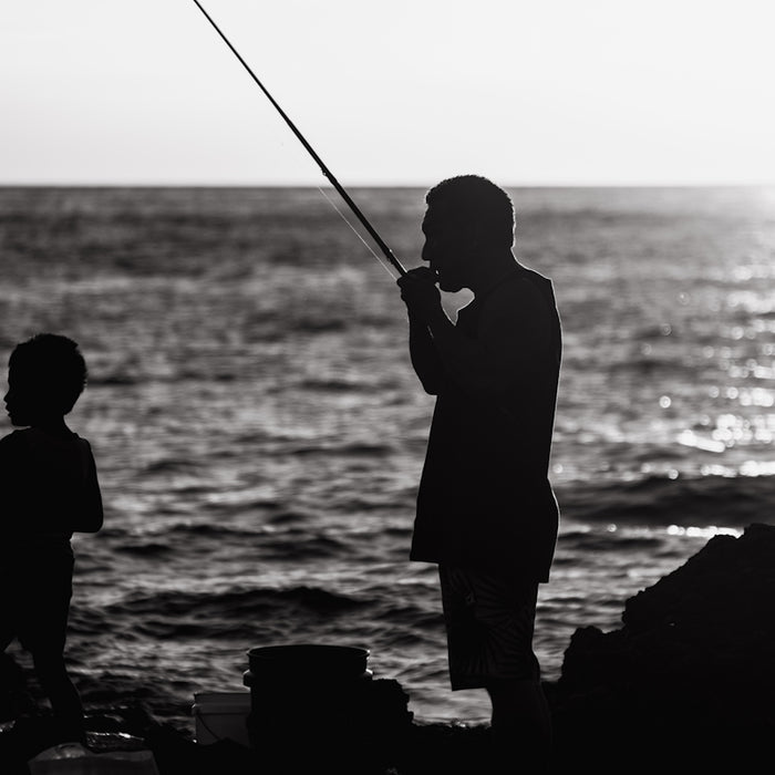 a black and white photo of a man and a child fishing