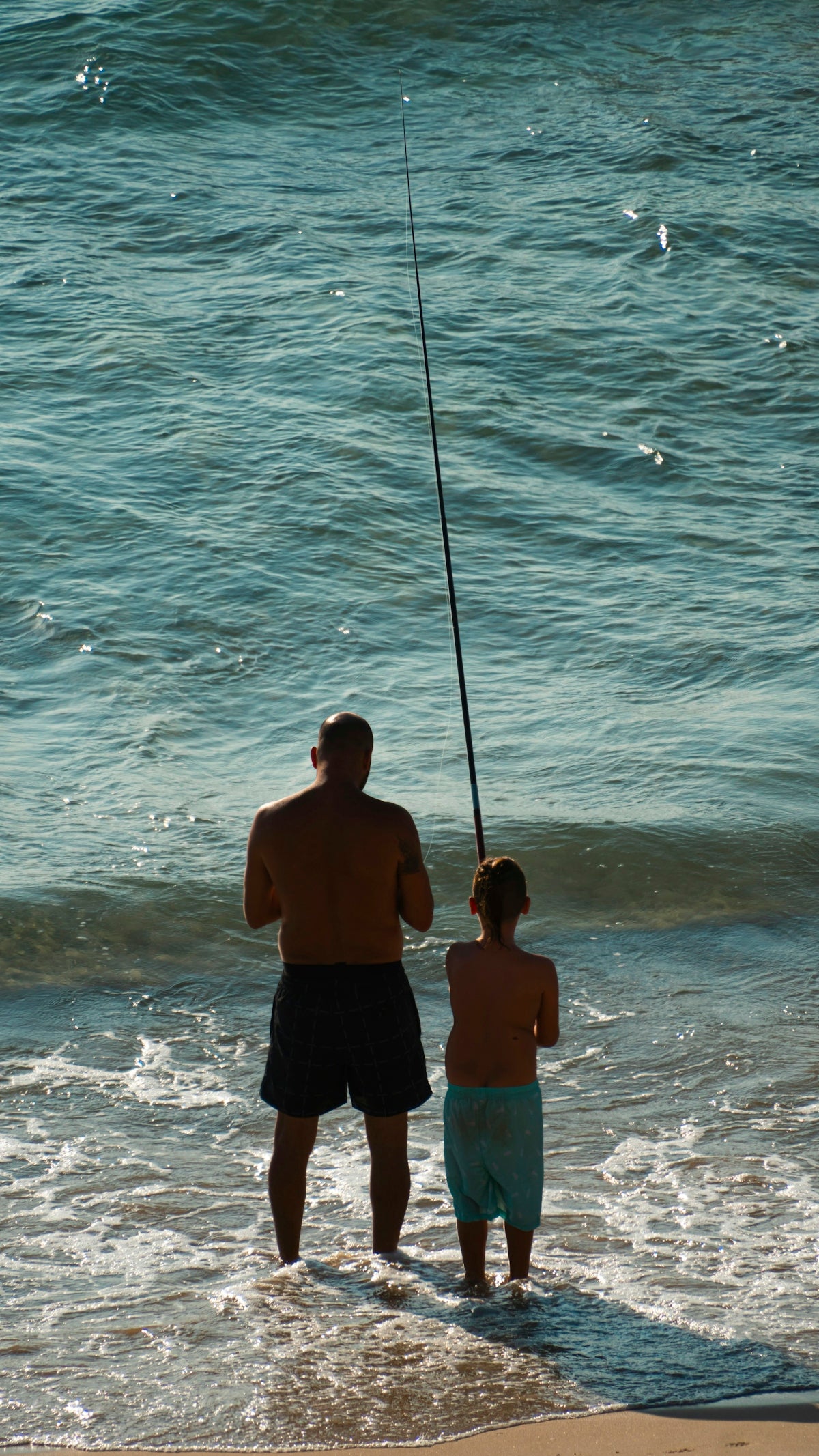 a man and a little girl fishing in the ocean