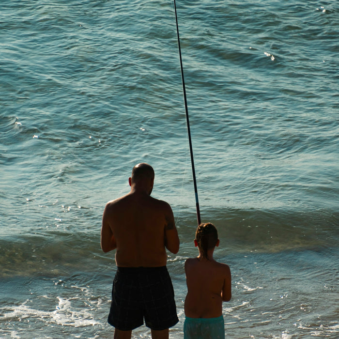 a man and a little girl fishing in the ocean