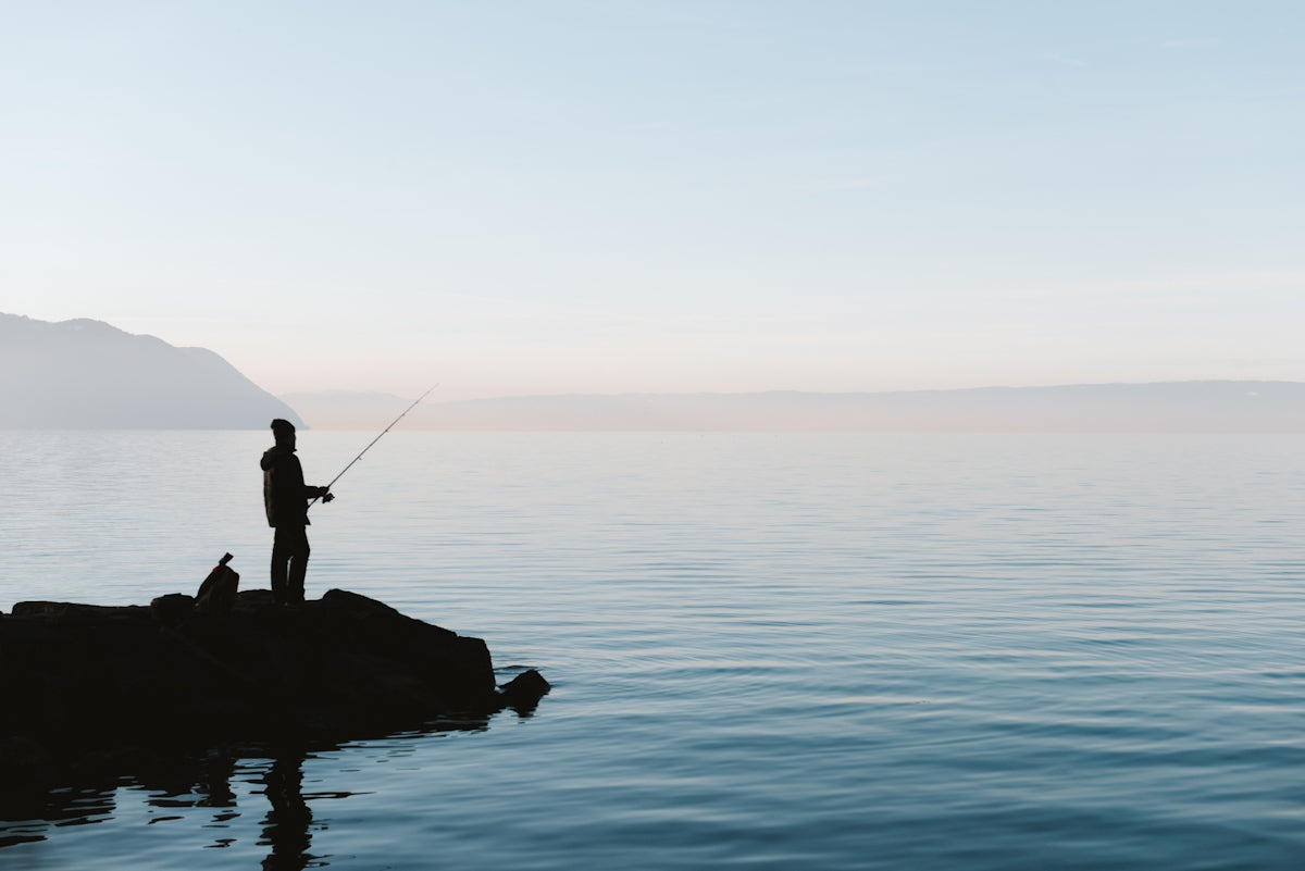 A man standing on a rock in the middle of a body of water
