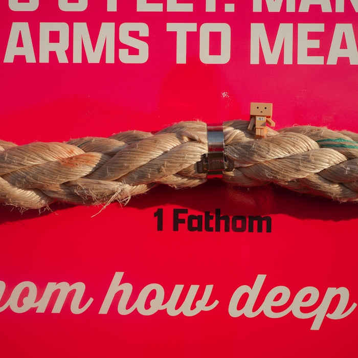 A tiny figure stands on a fathom-measured rope.