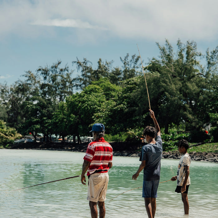 Three people are fishing in the shallow water.
