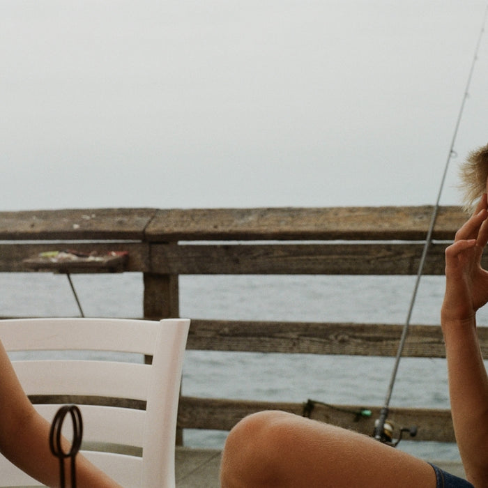 Two people are laughing while sitting on a pier.