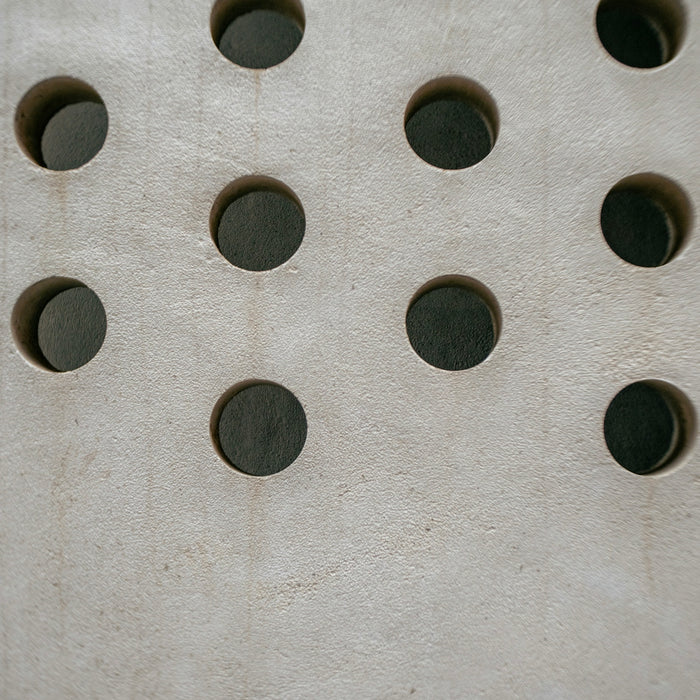 A pattern of circular holes in a light gray surface.